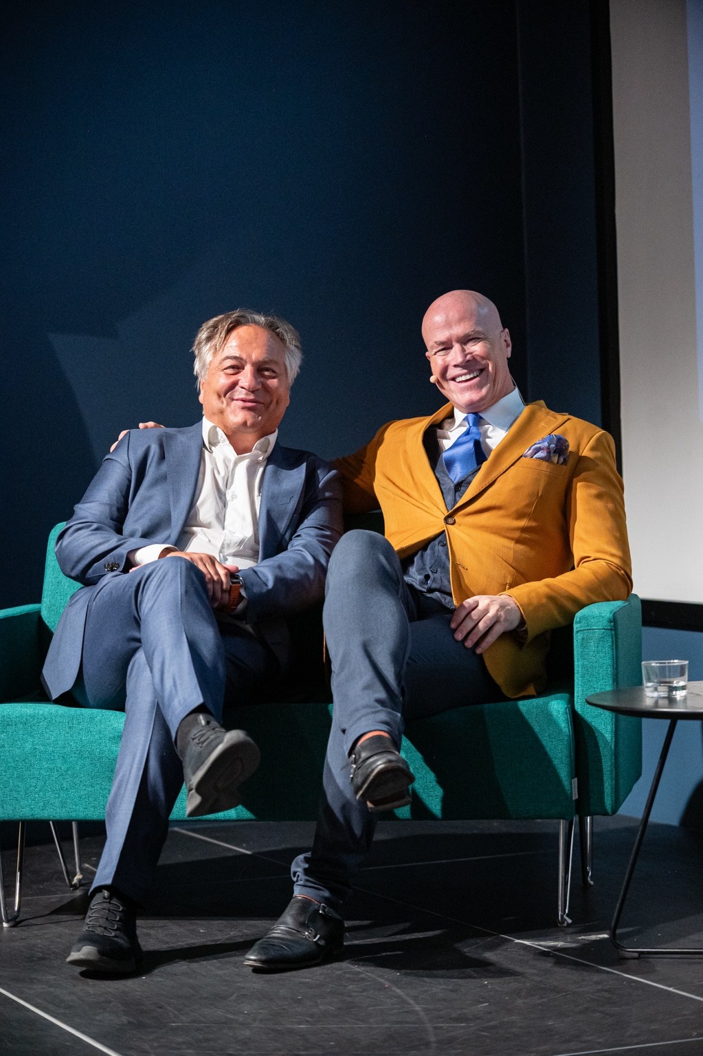 Are Johnsen og Svein Harald Røine smiler sammen i sofaen på scenen